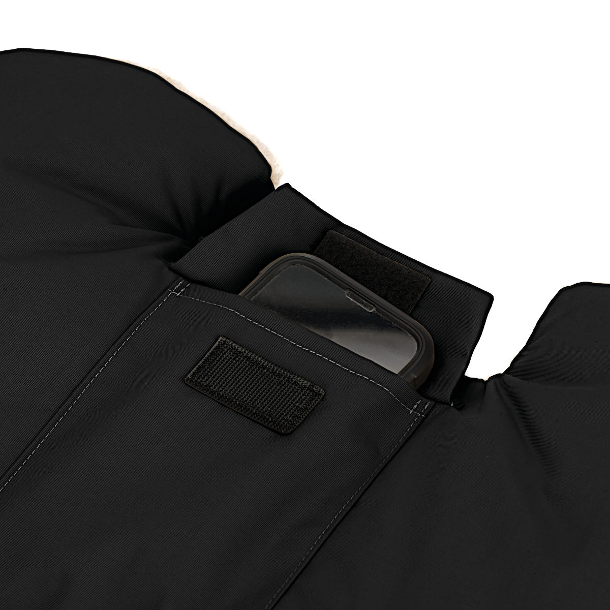 Nahaufnahme eines schwarzen Handwärmers mit kleiner Tasche auf der Oberseite, verschließbar mit Klettverschluss. Ein Smartphone ist darin verstaut, um den Stauraum zu demonstrieren.