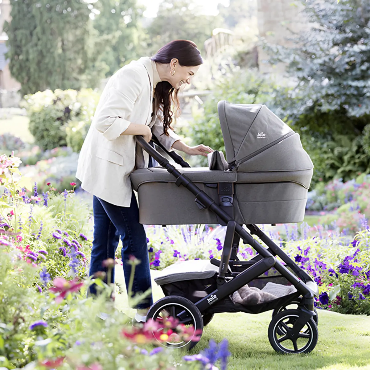 Eine Frau beugt sich liebevoll über die Babywanne des Kinderwagens und spricht mit ihrem Baby