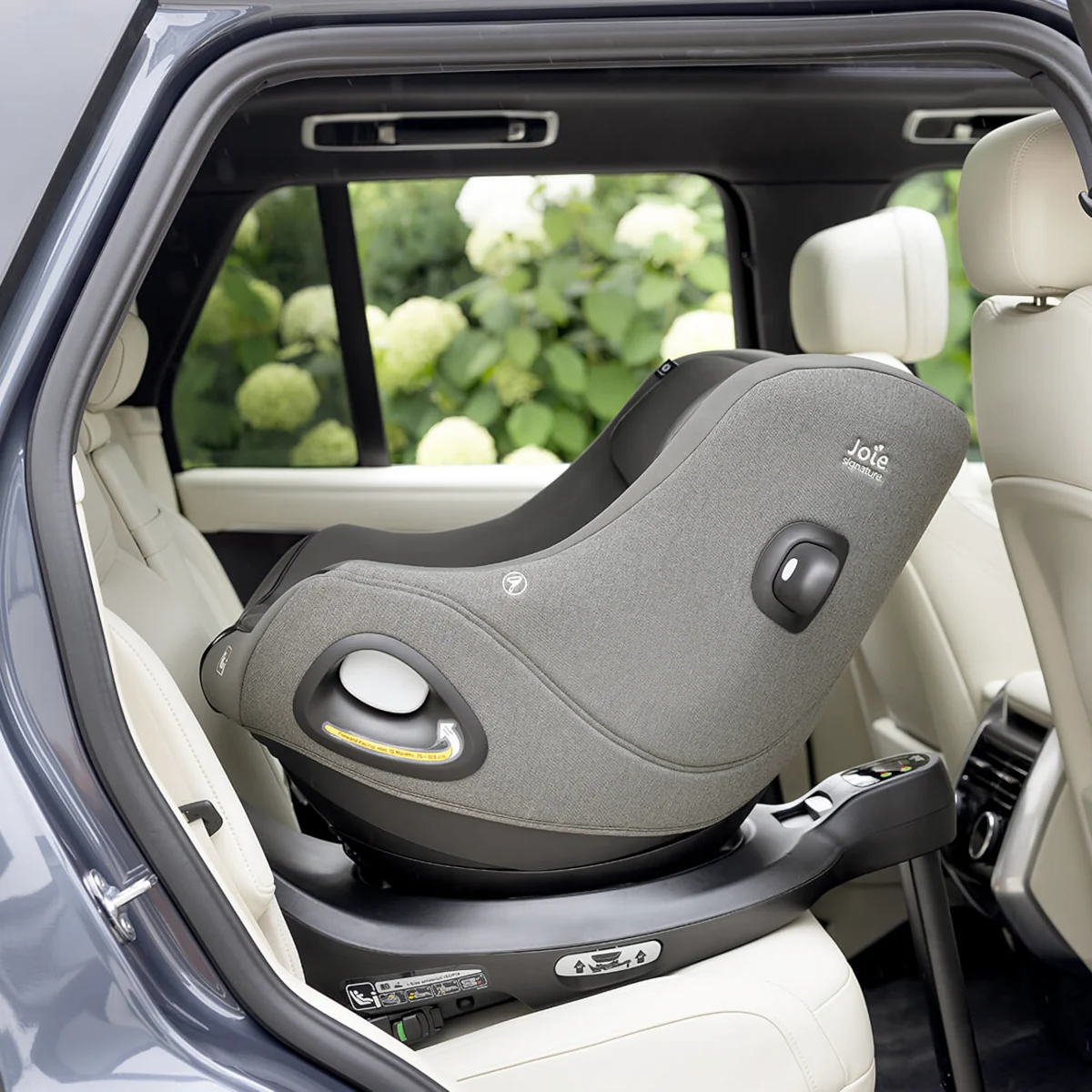 Ein grauer Joie Kindersitz ist rückwärtsgerichtet auf einer i-Base Encore im Auto installiert.