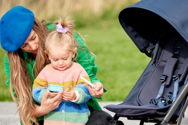 Joolz Aer+ Buggy Sitz Frau und Kind stehen neben einem Joolz Aer+ Buggy, der mit der Sitzfläche zur Kamera gedreht ist
